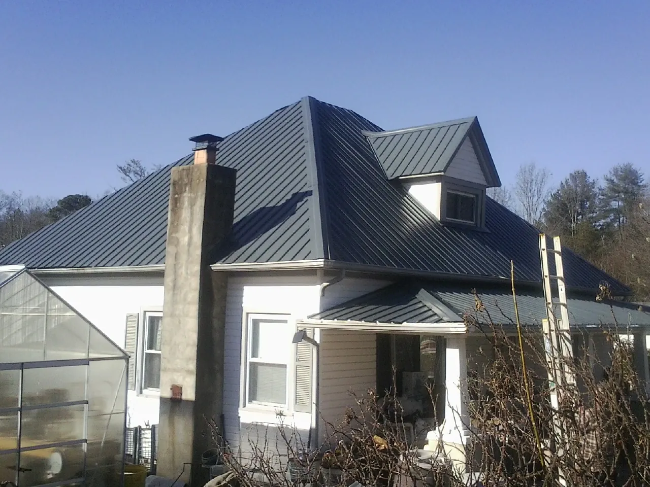 Dark blue standing seam metal roof on a white farmhouse with dormer — Slate & Tile Roof Repair by Roofing Brothers in Napavine