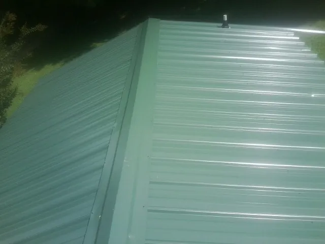 New green metal panels meeting at the ridge of a roof — Flat Roof Repair work by our crew in Napavine