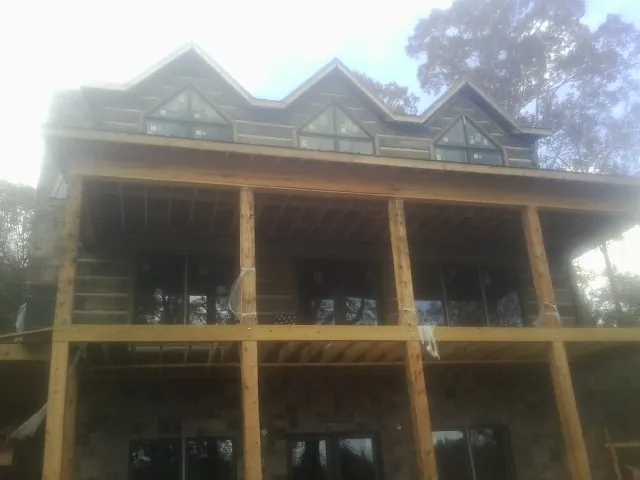 Dormers and porch framing on a large log home under construction — Roof Coating work by our crew in Napavine