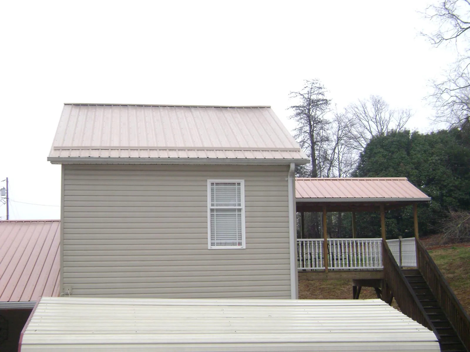 Tan metal roofs on a two story addition and attached porch, from a Roof Replacement job in Napavine